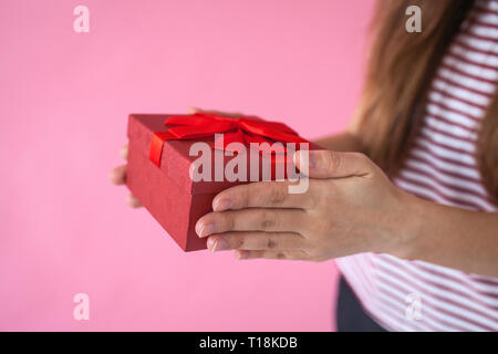 The girl holds in her hands a red box with a gift. Stock Photo
