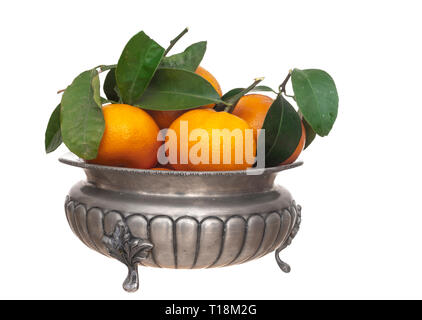 Small oranges, tangerines, with leaves in vintage pewter bowl, isolated on white. Stock Photo