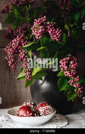 traditional decorated polish Easter eggs and lilac flowers in a vase Stock Photo
