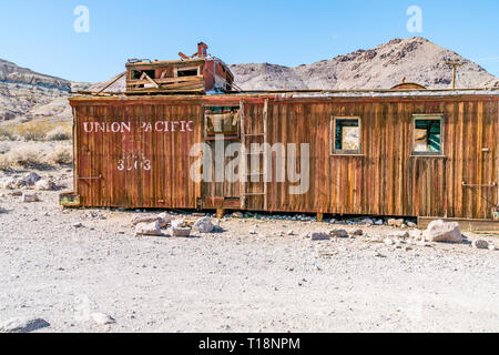 An abandoned, wheel-less Union Pacific caboose decaying in the Mojave Desert ghost town of Rhyolite. A caboose is a manned North American railroad car Stock Photo