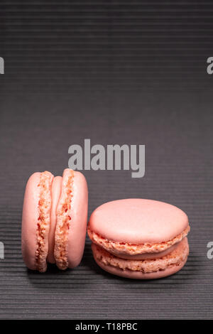 Colorful french macarons with strawberry flavor isolated on black background. Pastel colors - Image Stock Photo