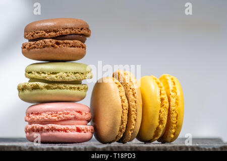 Assorted colorful french macarons isolated on white background placed on a slate stone. Pastel colors - Image Stock Photo