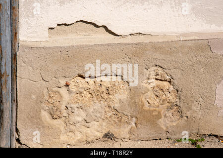 destroyed plaster on a house wall which falls off Stock Photo
