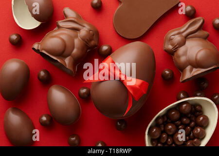 Easter composition with chocolate eggs and bunnies on red background, holiday concept Stock Photo