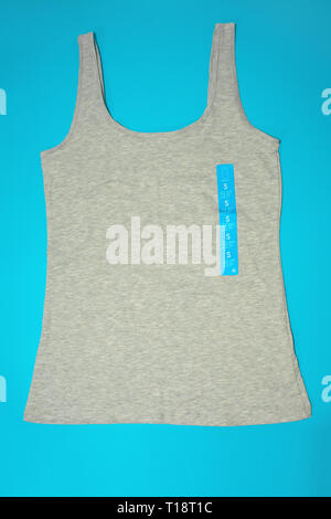 A flatlay top view of a casual gray female sleeveless top tank of a small size on blue background Stock Photo