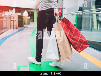 A picture of people's low part of the body. Human is holding shopping bagsin left hand. This human is in shopping mall Stock Photo