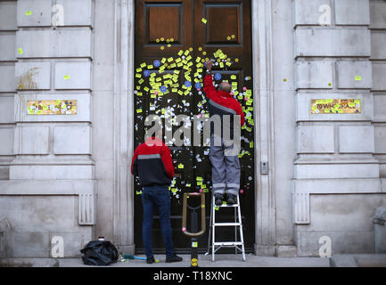 Workers peeling off stickers left on the Cabinet Office door on Whitehall, London, left by anti-Brexit campaigners after they took part in the People's Vote March.
