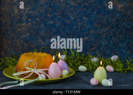 Easter bread on green plate and painted Easter eggs on dark stone table decorated with green grass Stock Photo