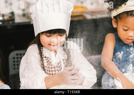 Cute mixed race and African American kid girls baking or cooking together in home kitchen. Education activity, youth culture, or smart young children  Stock Photo