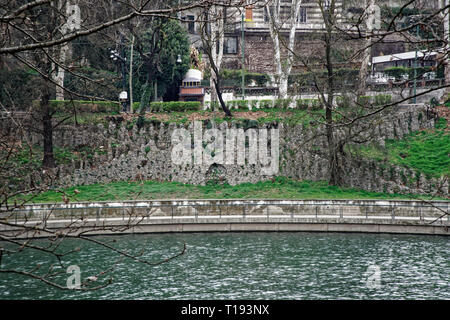 Old medieval stone walls along a street and water canal, in a tuscan village Stock Photo