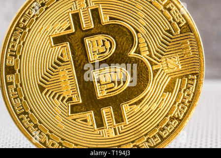 Close up macro front view of single golden bit coin on silver metallic background Stock Photo