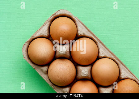 Raw hen eggs in a carton with a colourful background. Stock Photo