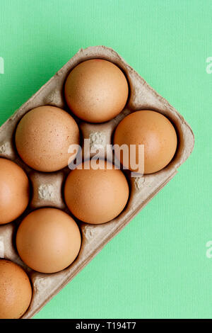 Raw hen eggs in a carton with a colourful background. Stock Photo