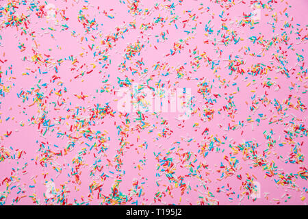 Birthday concept. Colorful sprinkles on pastel pink background, top view Stock Photo