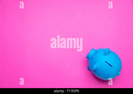 Savings concept. Piggy bank blue color against bright pink background, copy space, top view. Stock Photo