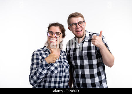 Nerds, geek, bespectacled and funny people concept - a couple of nerds in glasses show us thumbs up on white background Stock Photo