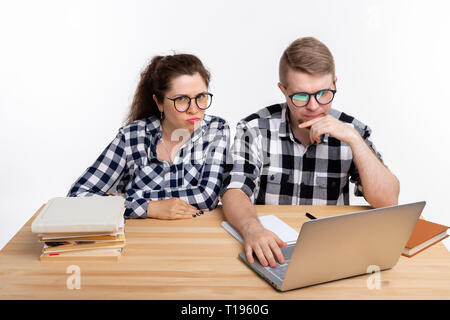 Nerds, geek, bespectacled and funny people concept - funny student couple in glasses sitting at the table Stock Photo