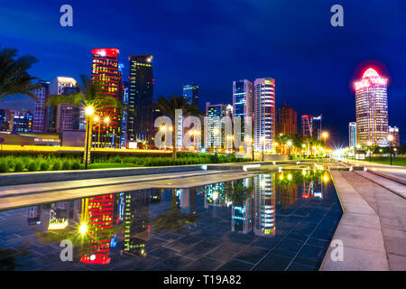 Doha West Bay high rises at night reflecting in the water of downtown park. Lighting skyscrapers of Doha skyline in Qatar, Middle East, Arabian Stock Photo