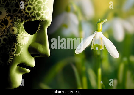 Working in harmony with nature concept with robotic face mask and brain cogs next to a delicate snowdrop flower in the garden Stock Photo