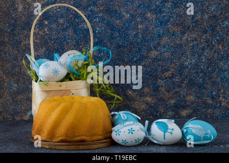 Easter bread and painted Easter eggs in a basket on dark stone table Stock Photo