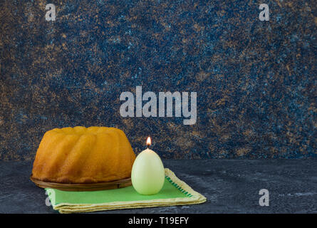 Easter bread and egg shaped candles on dark stone table Stock Photo