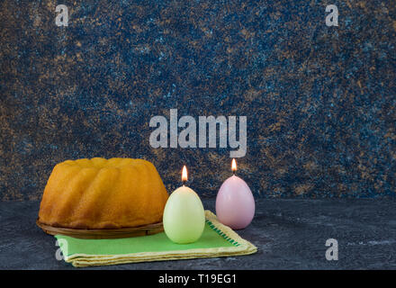 Easter bread and egg shaped candles on dark stone table Stock Photo