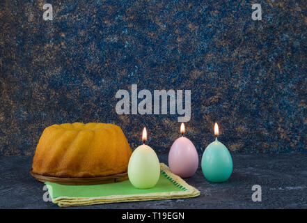 Easter bread and egg shaped candles on dark stone table Stock Photo