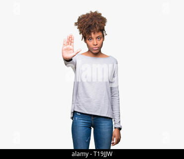 Beautiful young african american woman over isolated background doing stop sing with palm of the hand. Warning expression with negative and serious ge Stock Photo