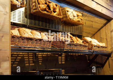 Baskets with different types of bread on the shelf in the bakery shop. Stock Photo