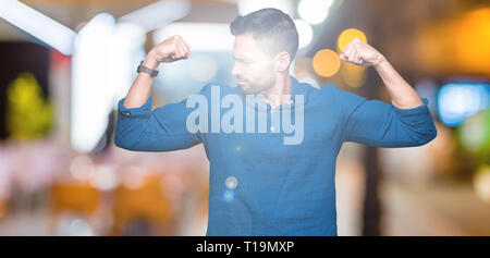 Young handsome man over isolated background showing arms muscles smiling proud. Fitness concept. Stock Photo