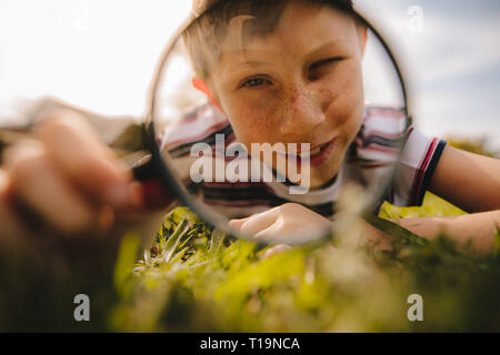 Boy looking through magnifying glass. cute boy exploring with magnifying glass. Stock Photo