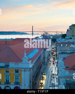 Aerial view of Lisbon Old Town street at twilight. Port and bridge in the background. Portugal