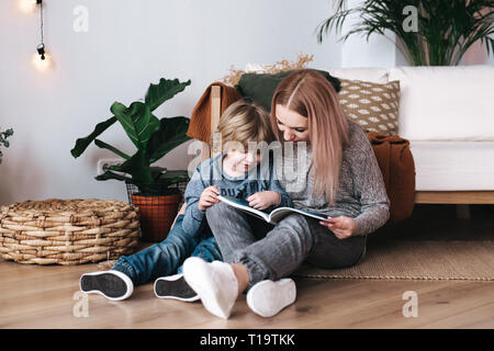 Mother and son sitting and reading book together at home Stock Photo