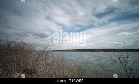 Wide Angle View of Large Lake from the the Shoreline behind dry branches Stock Photo