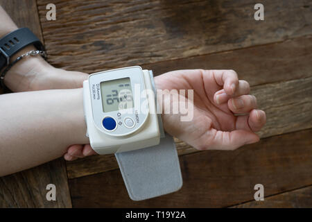middle aged woman takes her blood pressure at home Stock Photo