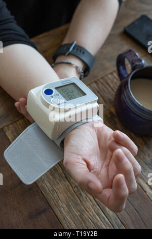 middle aged woman takes her blood pressure at home Stock Photo