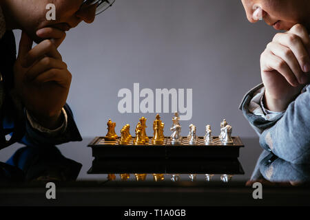 Two unrecogniazble businessmen thinking over moves while playing chess against gray background Stock Photo