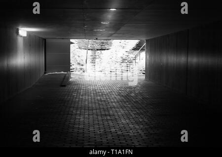 An underground passage in winter with some snow on the stairs in black and white Stock Photo