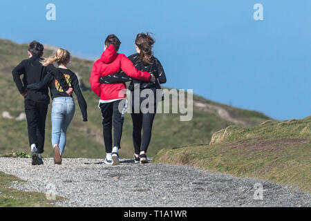 Young teenagers with their arms around each other walking along a footpath. Stock Photo
