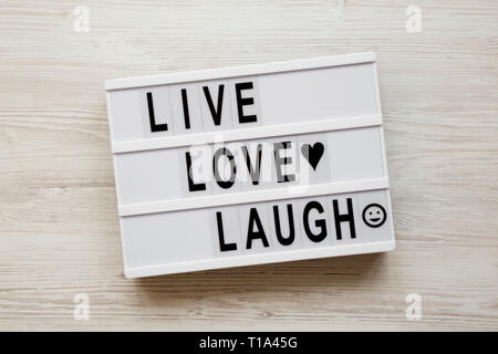'Live Love Laugh' words on lightbox over white wooden background, top view. Flat lay, overhead, from above. Stock Photo