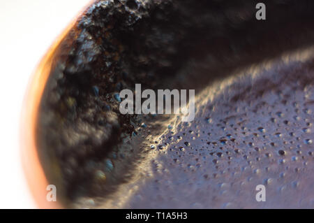 freshly brewed natural black coffee with foam in traditional copper coffee pot, close-up Stock Photo