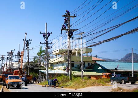 Electricians working on a power pole, filled with complex communication lines.  Stock Photo