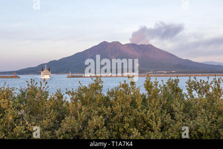Eruption of the Vulcan Sakurajima and Kagoshima Ferry arriving the Port during summer sunset. Located in Kagoshima, Kyushu, South of Japan. Stock Photo