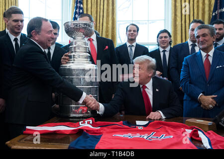 Washington, DC, USA. 25th Mar, 2019. US President Donald J. Trump (2-R) shakes hands with Commissioner of the National Hockey League (NHL) Gary Bettman (L), beside the Stanley Cup, players and staff of the NHL 2018 Stanley Cup Champions, the Washington Capitals; in the Oval Office of the White House in Washington, DC, USA, 25 March 2019. Also in the picture is Capitals owner Ted Leonsis (Front R). Credit: Michael Reynolds/Pool via CNP | usage worldwide Credit: dpa/Alamy Live News Stock Photo