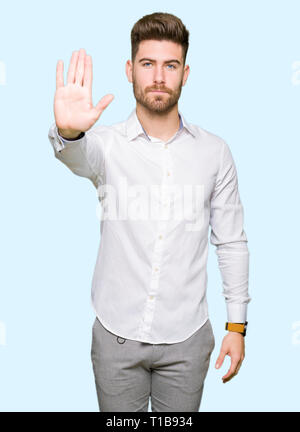 Young handsome business man doing stop sing with palm of the hand. Warning expression with negative and serious gesture on the face. Stock Photo