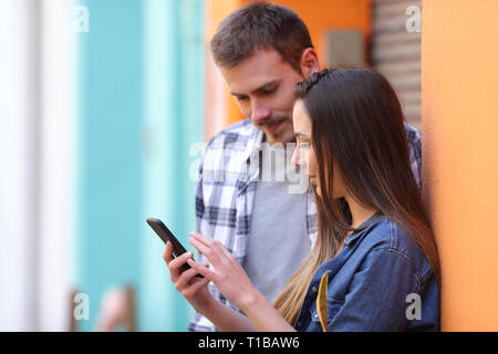 Serious couple checking smart phone messages in a colorful street Stock Photo