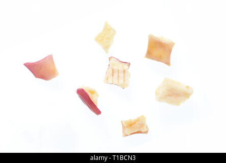 Close up photo image of cube sliced dry red apple isolated on white background, scattered pieces of dried fruit flakes, scattered dry red apple flakes Stock Photo
