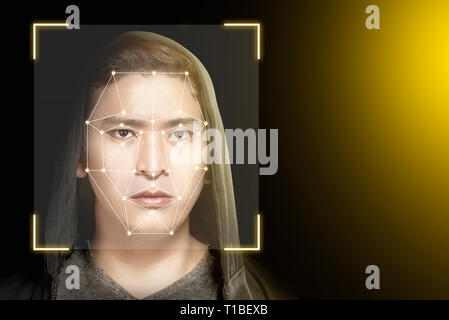 Young asian man in black hoodie using face recognition over dark background. Modern technology concept Stock Photo