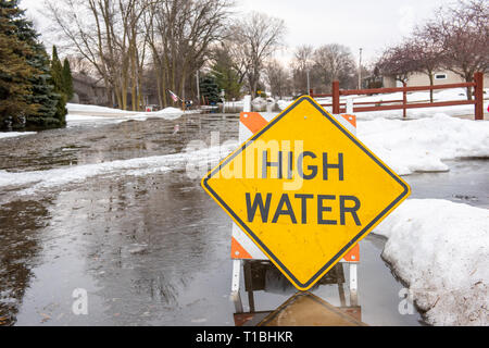 A high water sign is sitting in a flooded street after a heavy rain and signifcant snow melt. Stock Photo