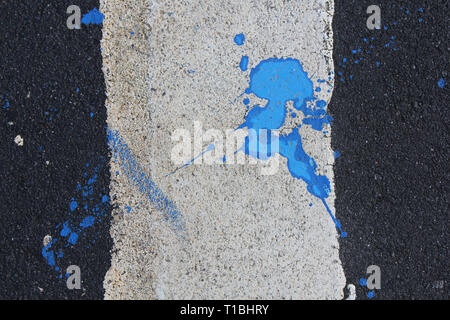 Blue paint is poured on asphalt. Abstract background Stock Photo